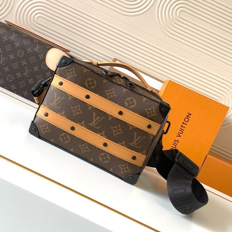 Louis Vuitton monogram canvas hard-sided trunk bag with tan leather stripes, black trim, and a black shoulder strap, shown with an orange Louis Vuitton box on a white surface.