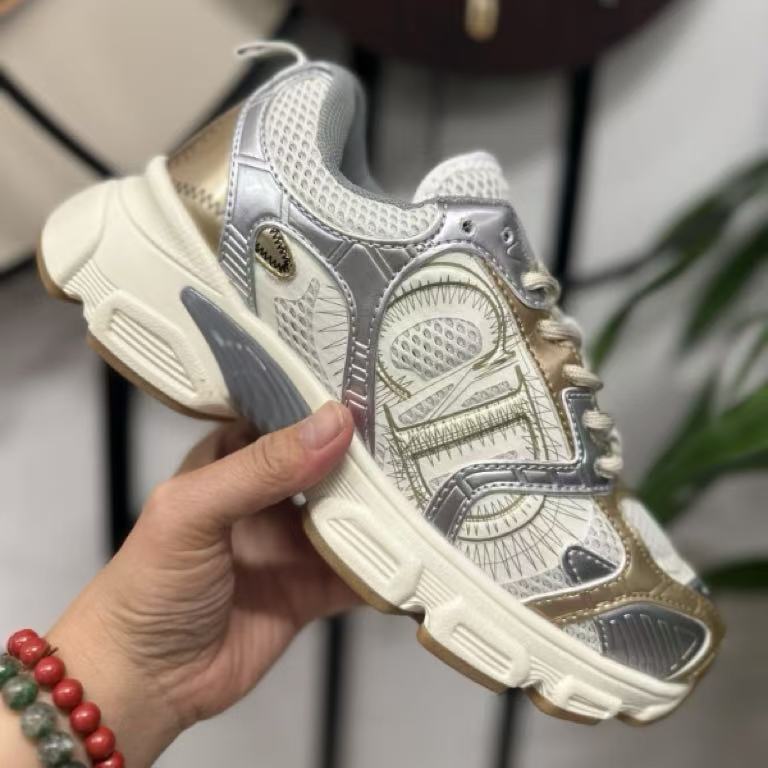 White and gold sneaker held by a hand with a blurred background