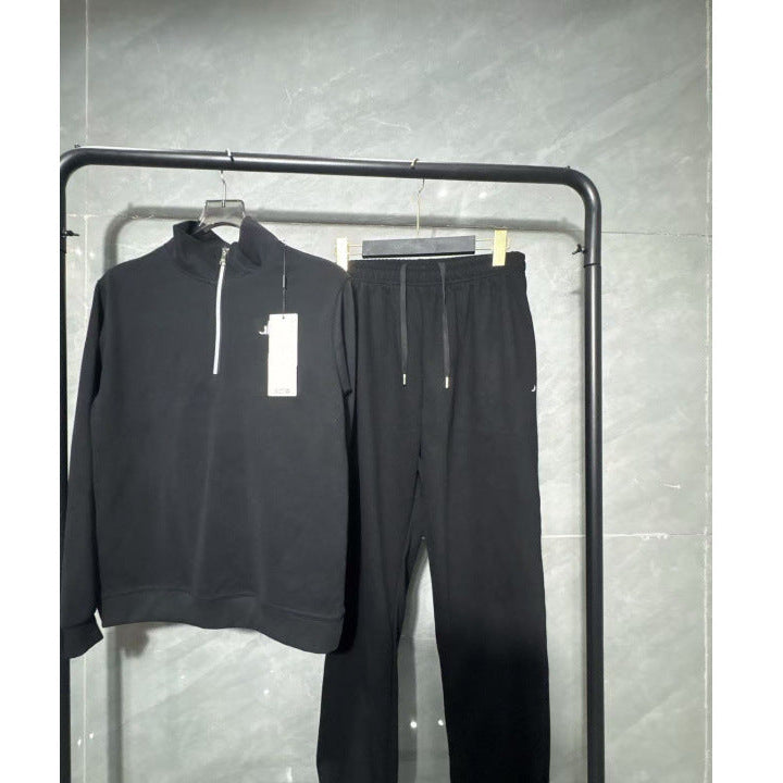 Black tracksuit on a rack against a gray wall