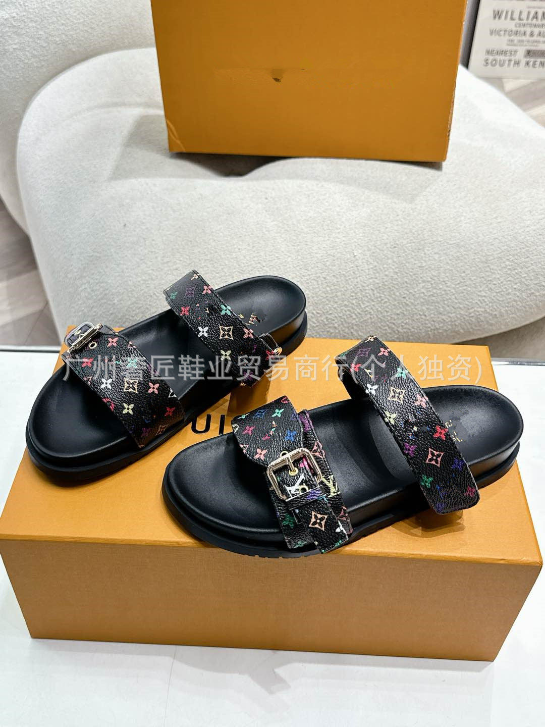 Black sandals with colorful straps on a Louis Vuitton box