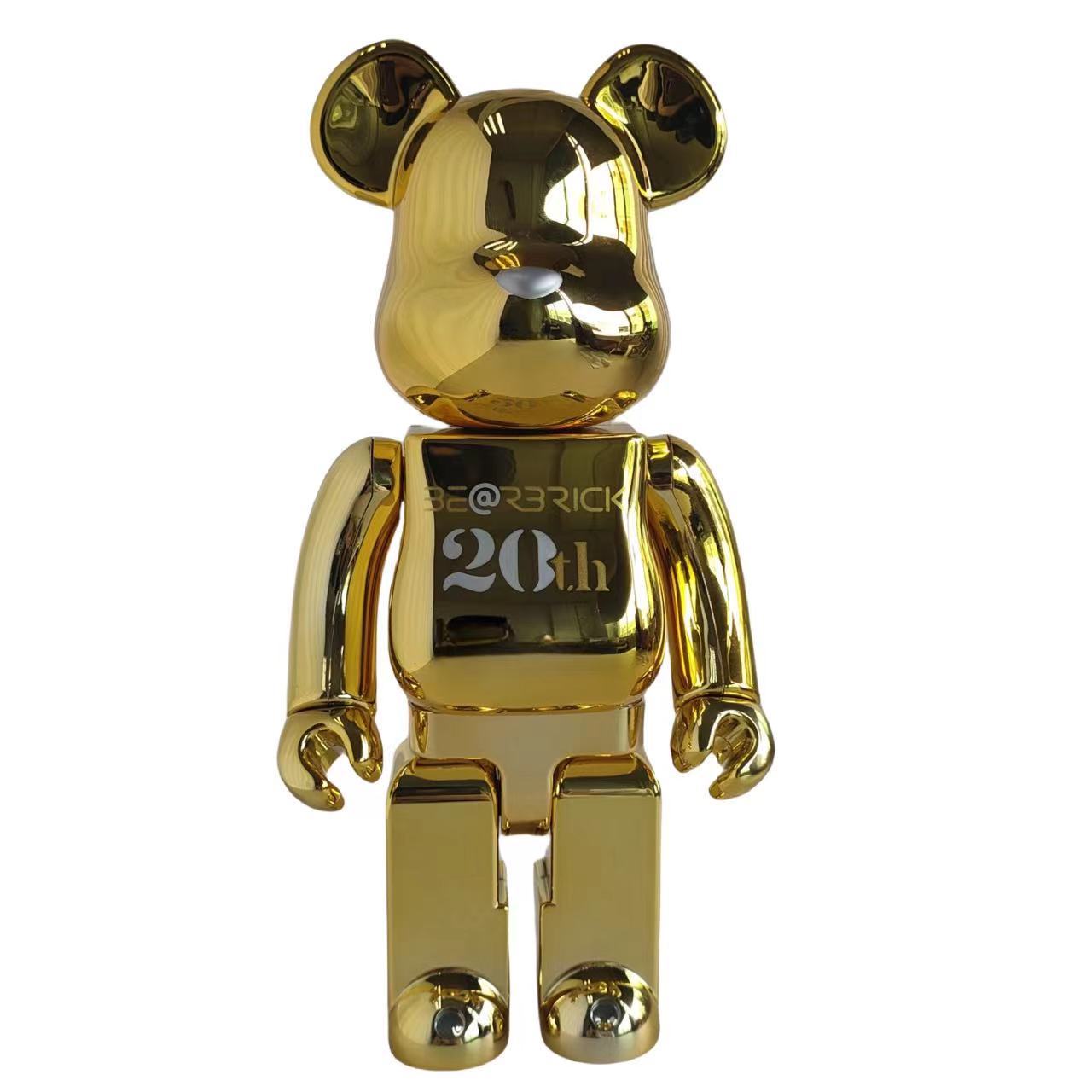 A shiny metallic gold Bearbrick toy figure with 'BE@RICK 20th' printed on its chest, isolated on a white background.