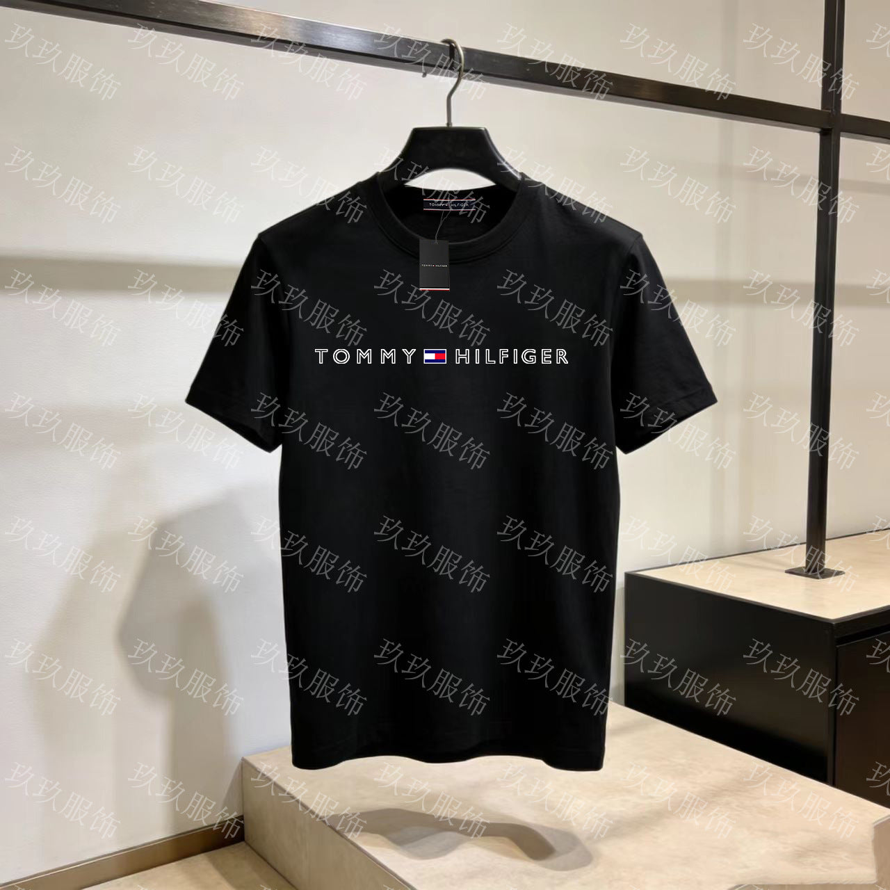 Black Tommy Hilfiger t-shirt on a hanger against a light background