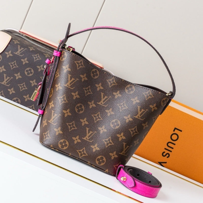 Louis Vuitton monogram canvas shoulder bag with a bright pink leather handle and trim, displayed next to its orange Louis Vuitton box on a white surface.