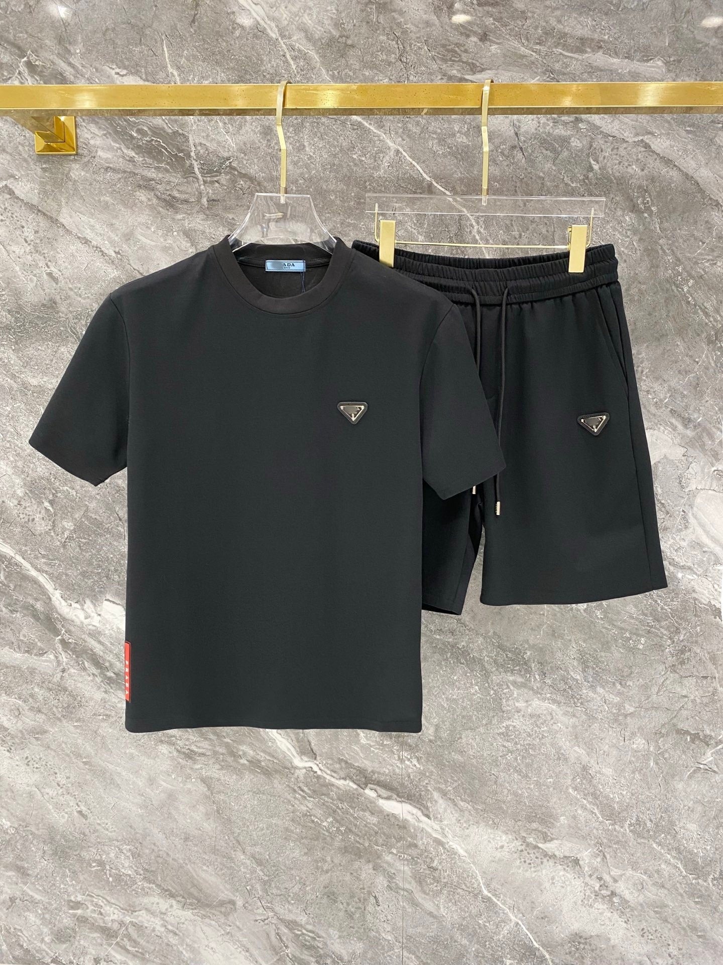 Black t-shirt and shorts set with brand logo on a marble surface