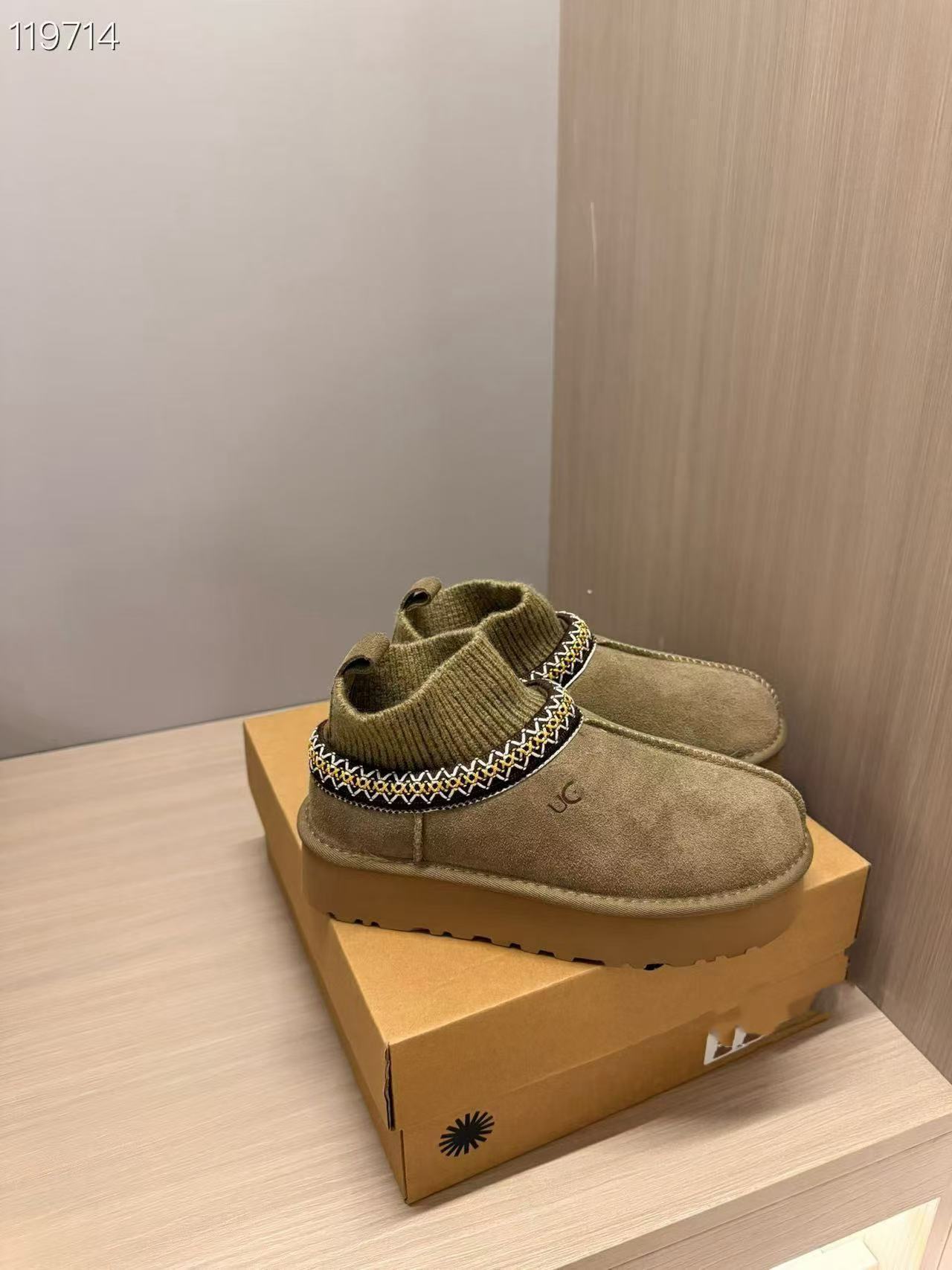 A pair of UGG mini slip-on boots in olive green suede with a knit trim, displayed on top of their original tan cardboard box.