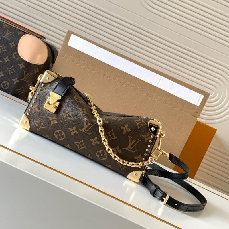 Louis Vuitton monogram shoulder bag in brown coated canvas with gold-tone hardware, a black leather strap, and a gold chain detail, displayed on a white surface with a Louis Vuitton box in the background.