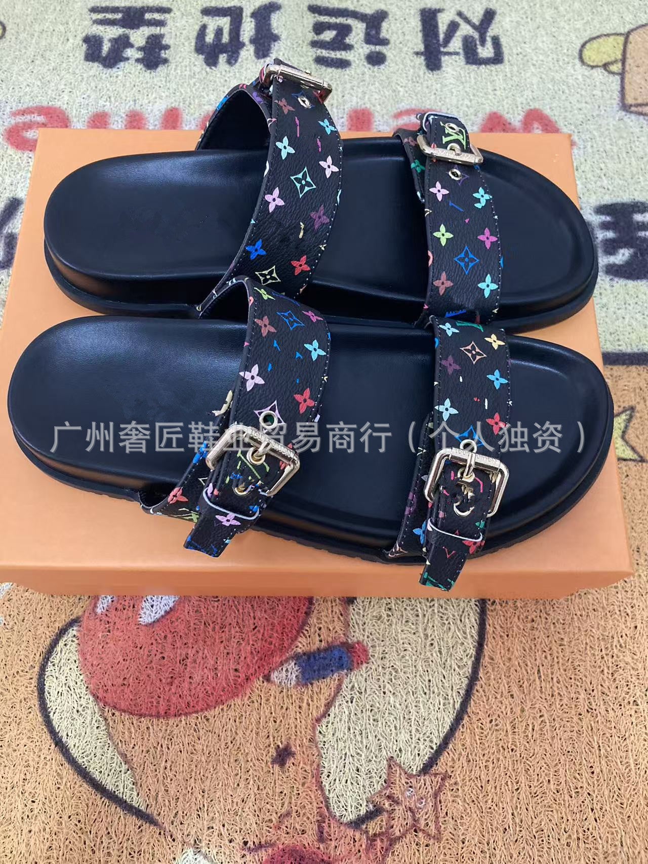 Black sandals with colorful straps on an orange box, with text in the background