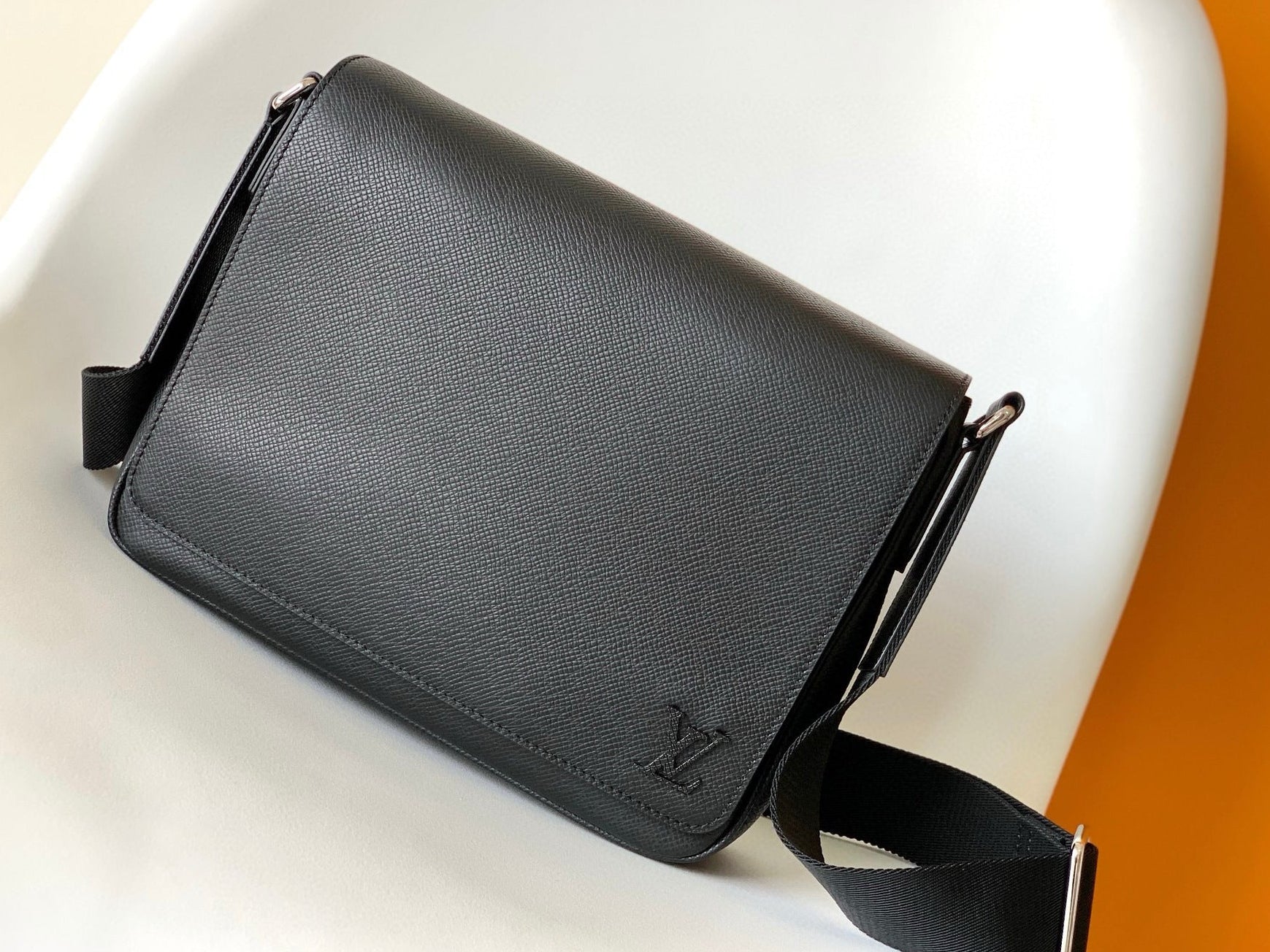 Black leather bag with a visible brand logo on a white surface.