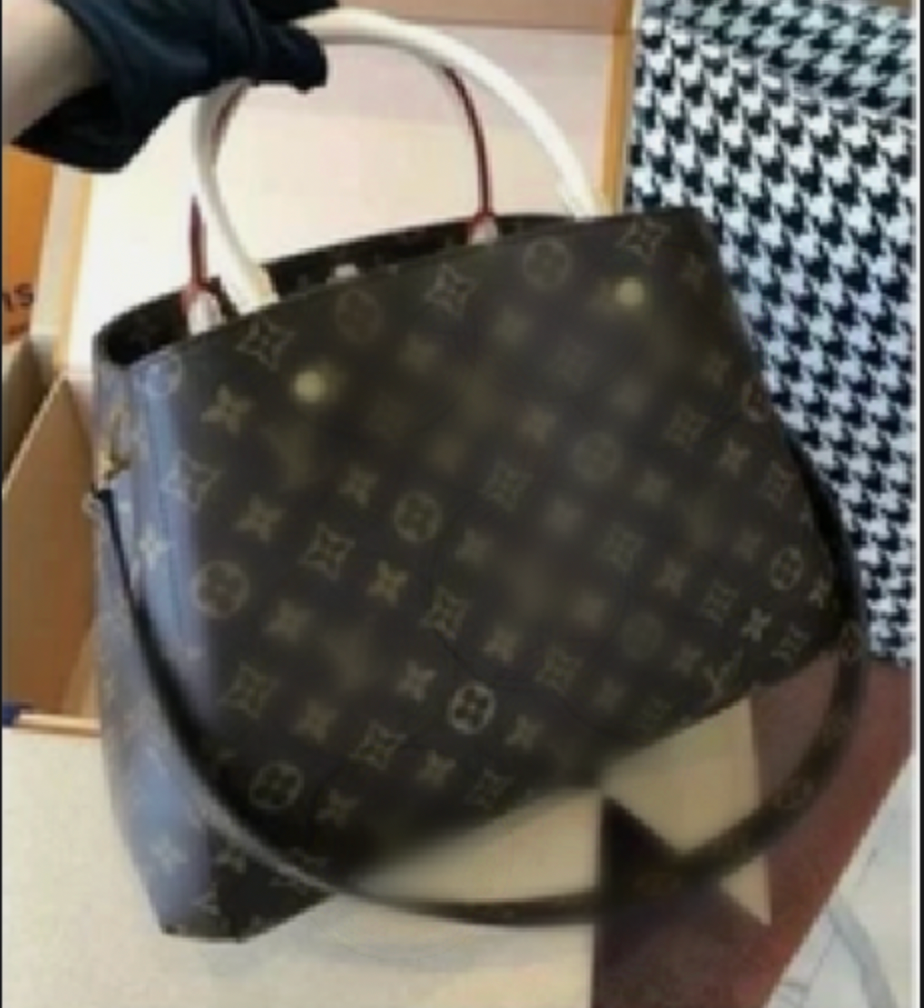 Designer handbag with monogram pattern held by a gloved hand.