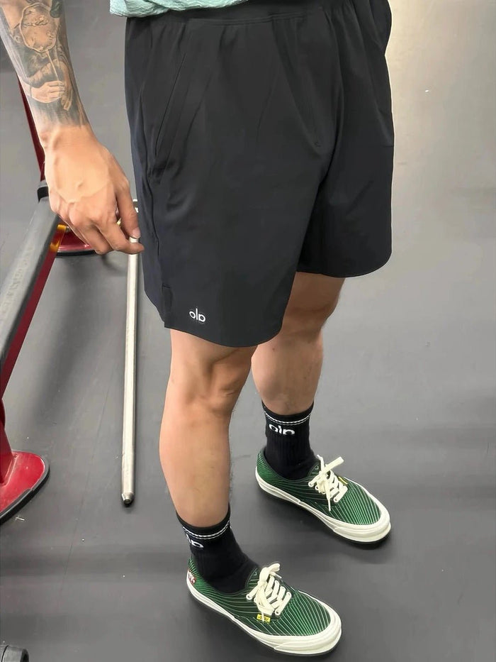 Person wearing black shorts and green sneakers on a gray background