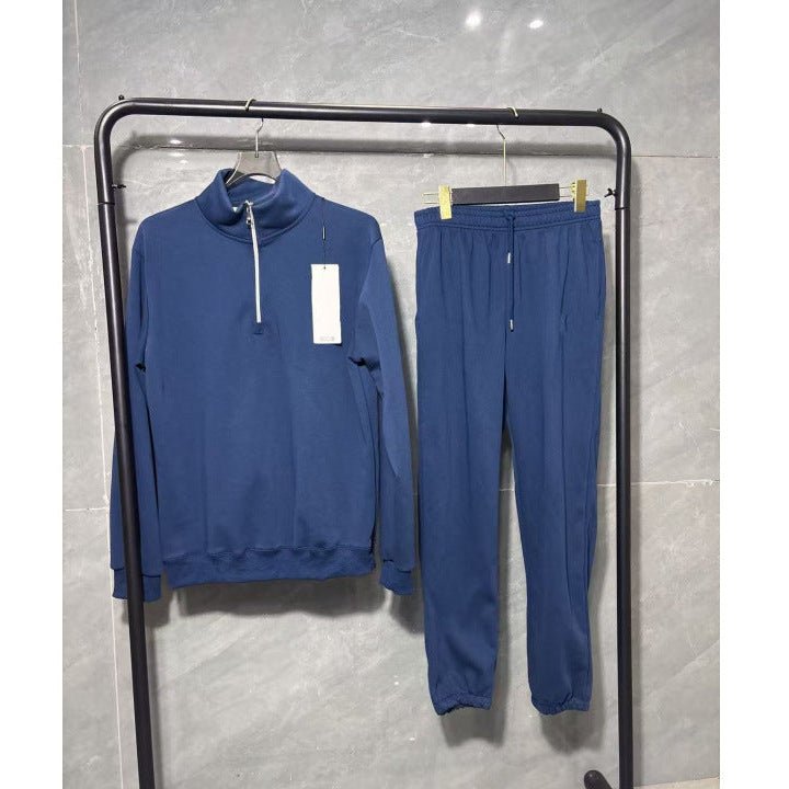 Blue tracksuit on a black rack against a gray tiled wall