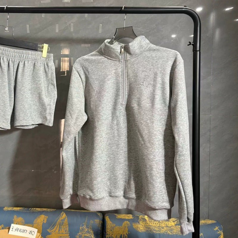 Gray zip-up sweatshirt on a hanger against a dark background