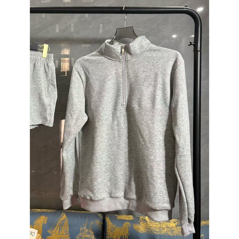 Gray zip-up sweatshirt on a hanger against a dark background