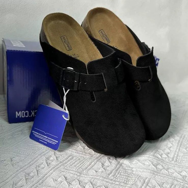 Black clogs with a tag on a textured surface