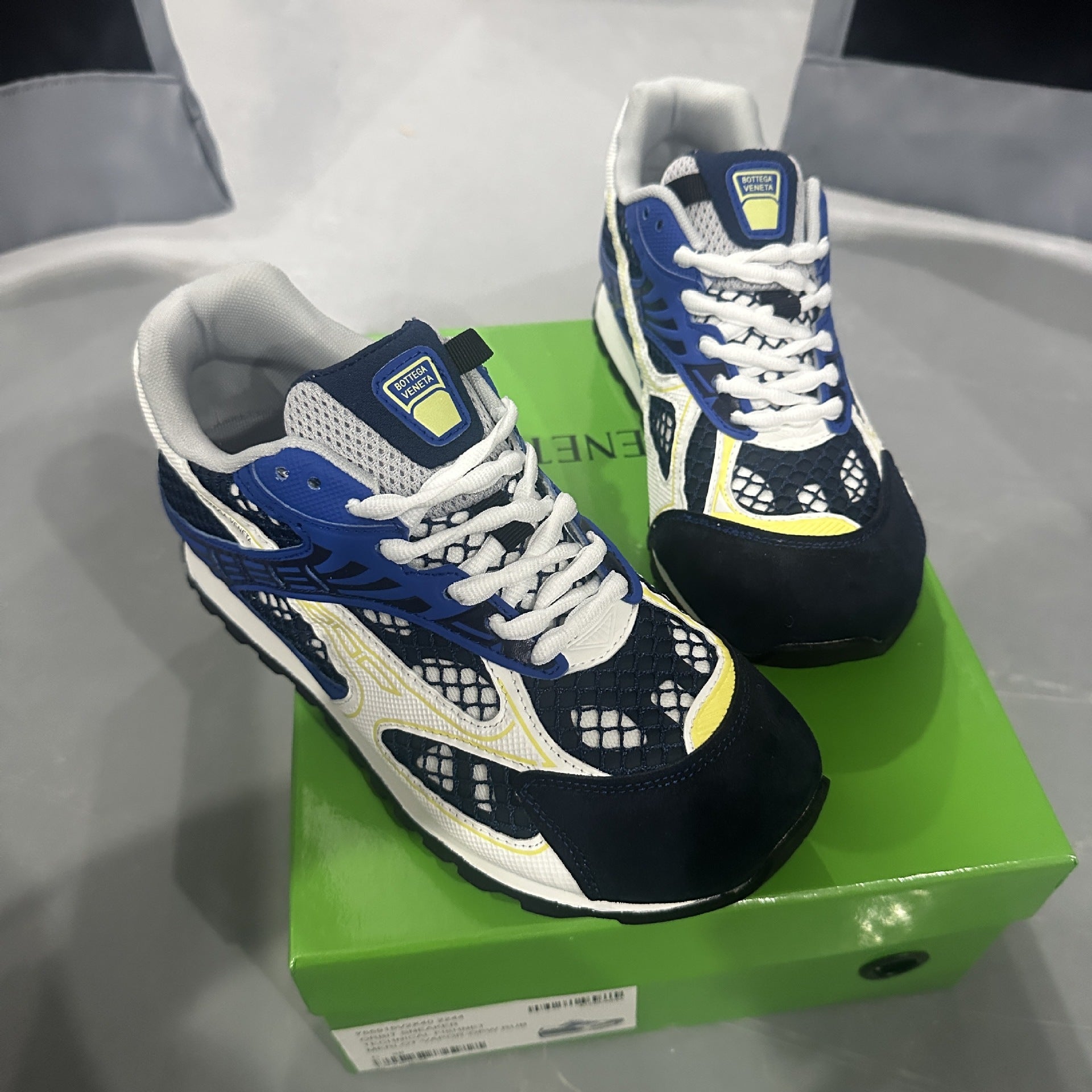 Blue and white sneakers with yellow accents on a green box