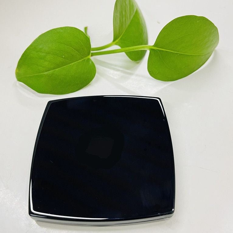 Black square plate on a white background with green leaves