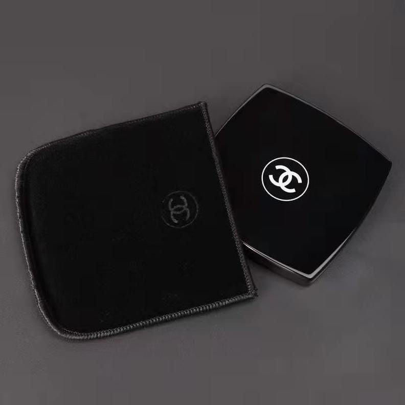 Two black jewelry boxes with Chanel logo on a dark background