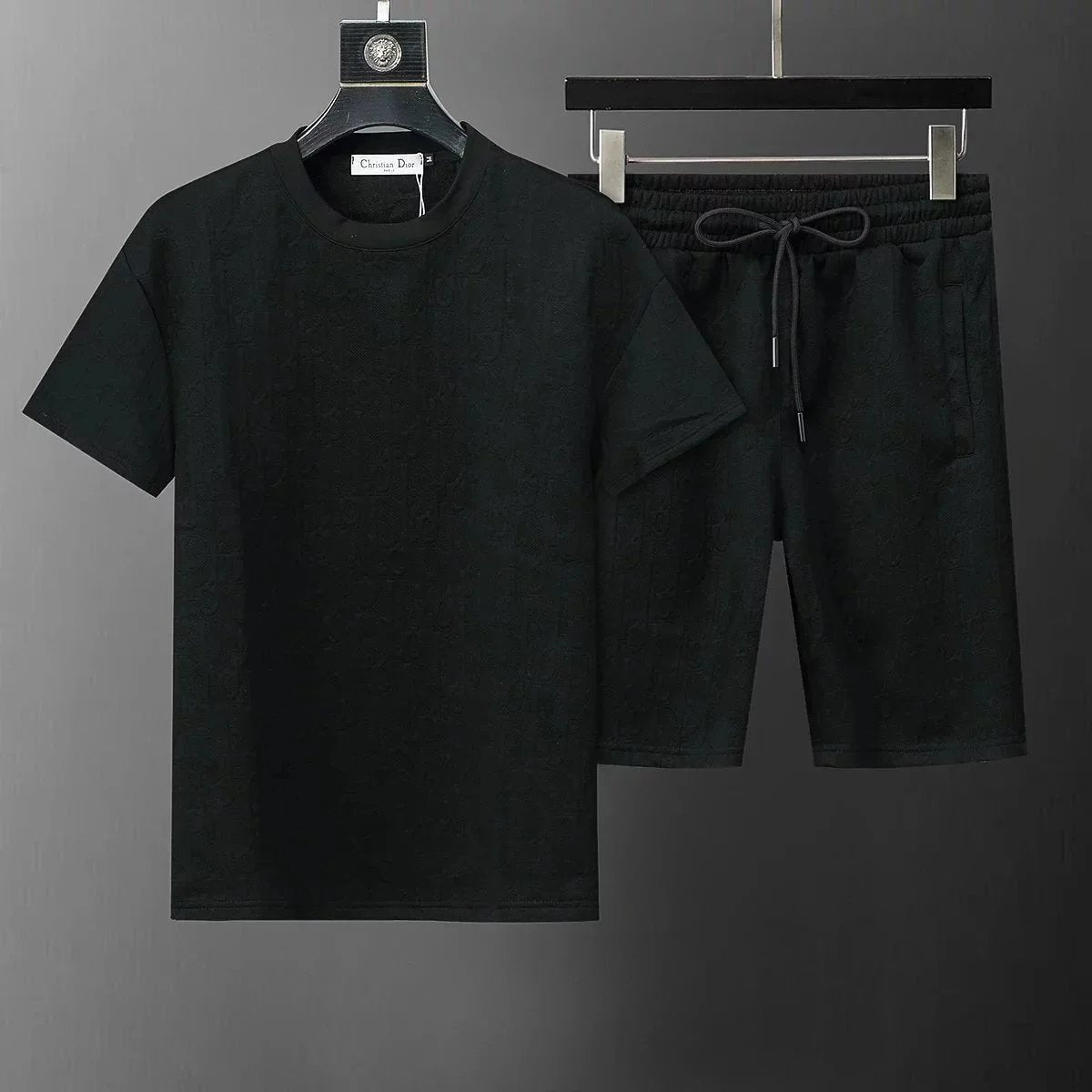 Black t-shirt and shorts set on hangers against a dark background