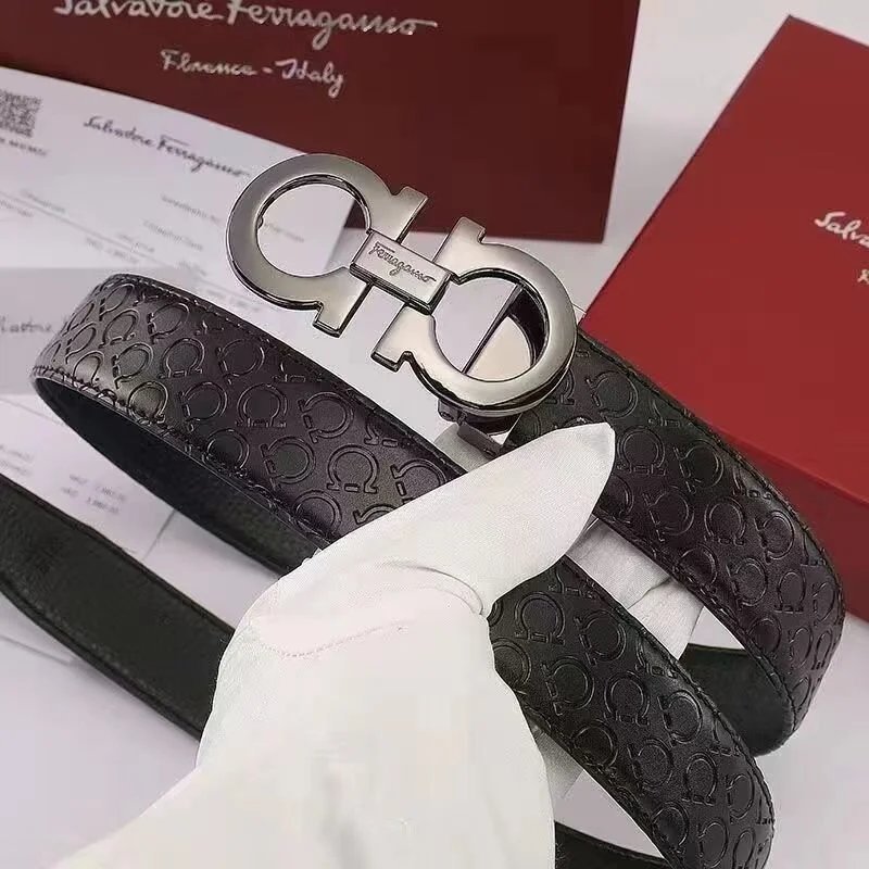 Black leather belt with Ferragamo logo held by a gloved hand, with a red box in the background.