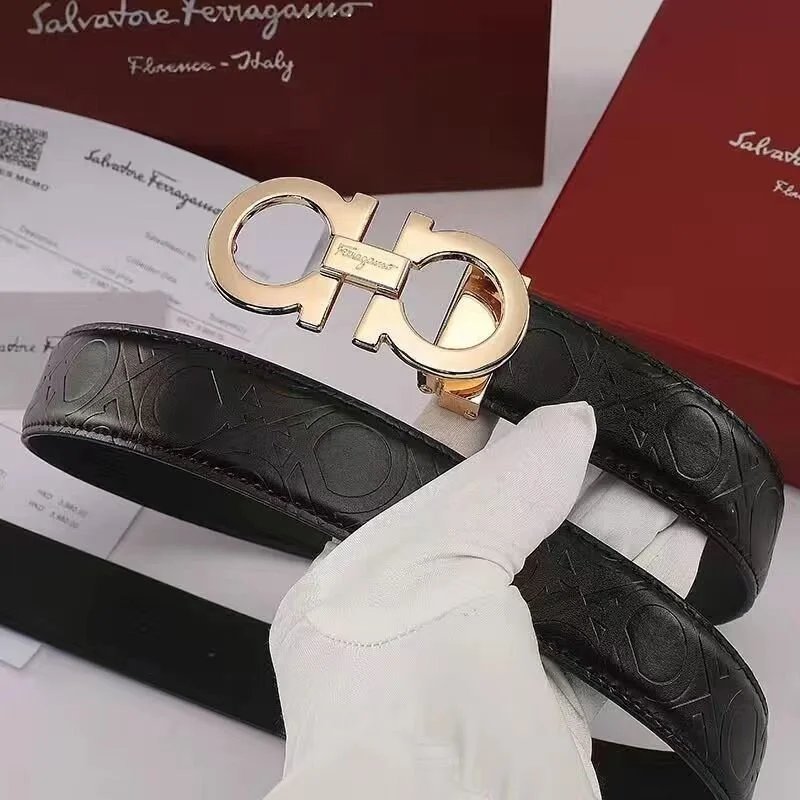 Black leather belt with gold Salvatore Ferragamo buckle held by a gloved hand, with brand packaging in the background.