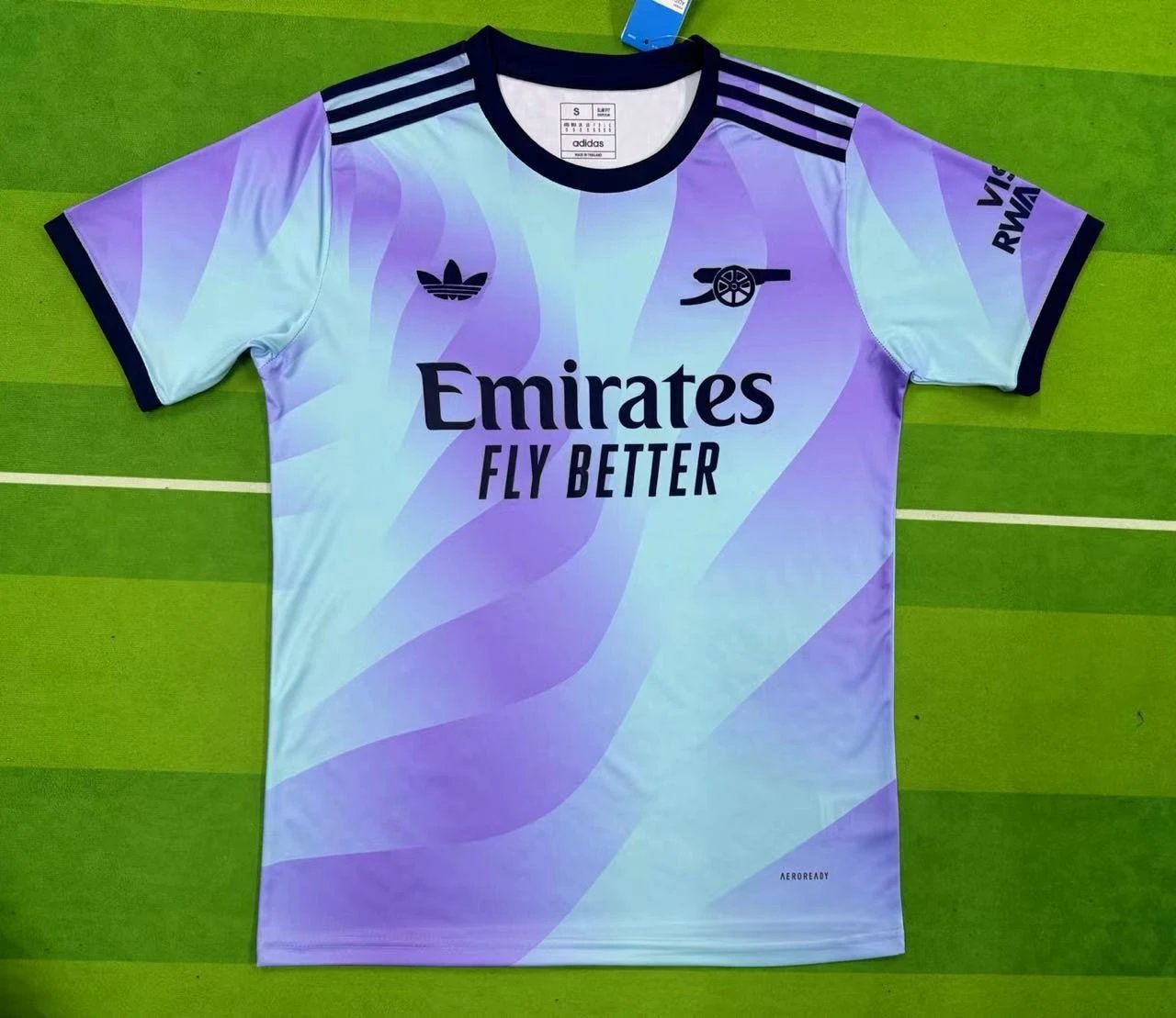 Purple and white sports jersey with Adidas and Emirates branding on a green surface