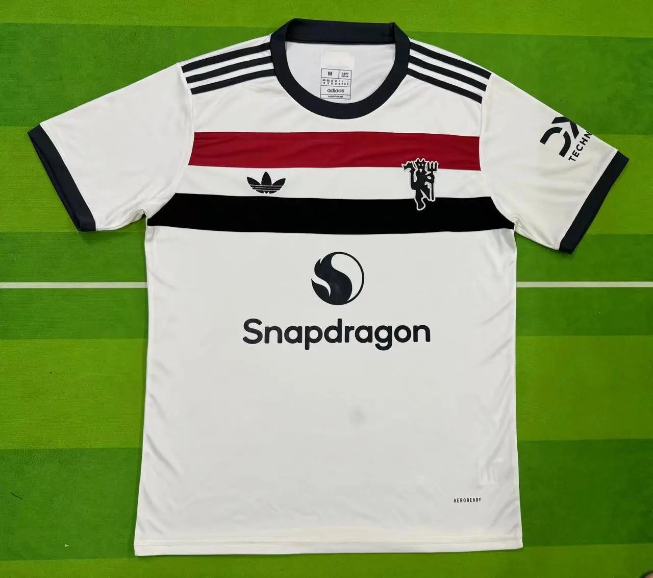 White sports jersey with black and red accents on a green background