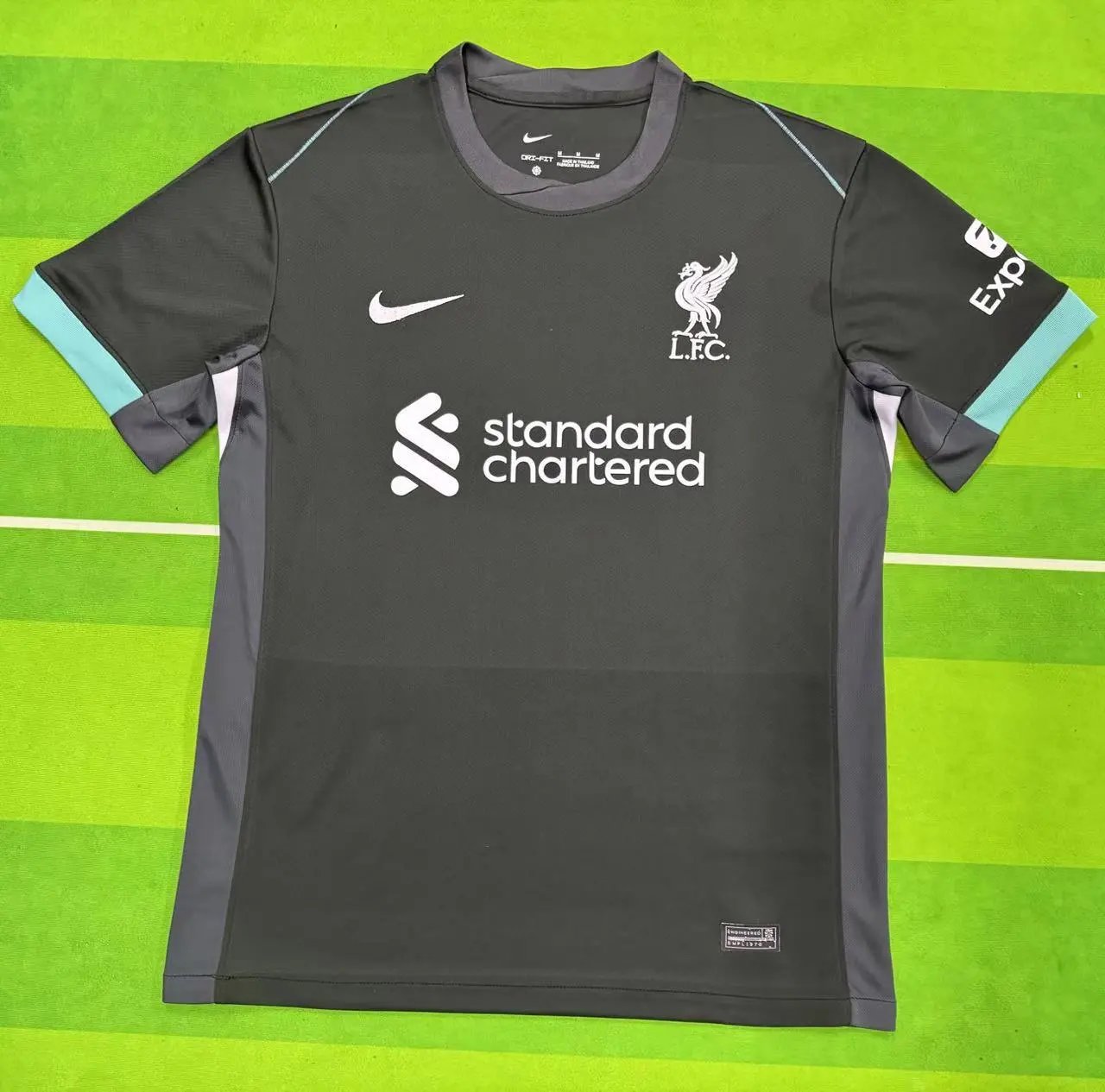 Gray sports jersey with Nike and Standard Chartered logos on a green background