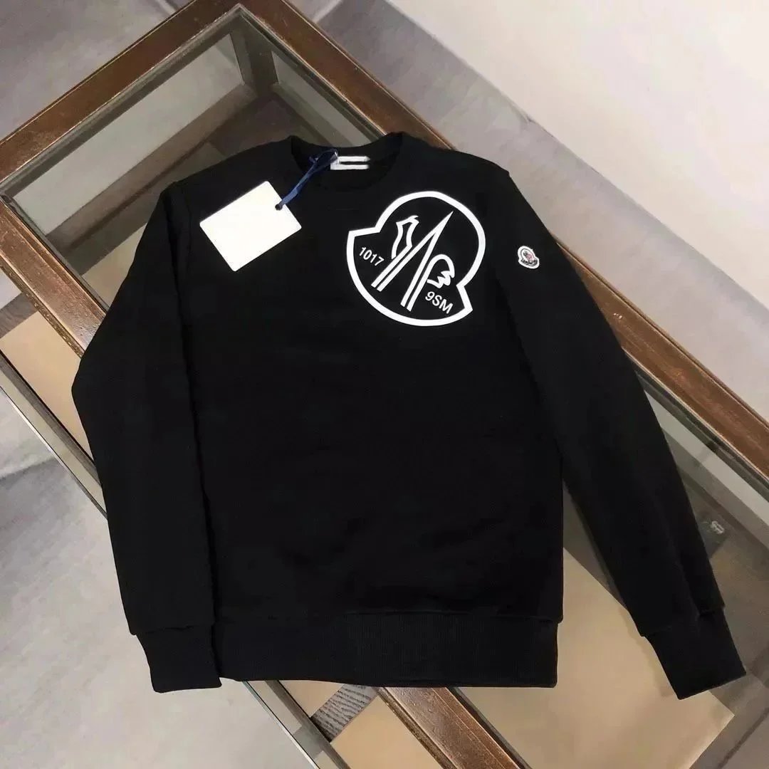 Black sweatshirt with a logo and tag on a reflective surface