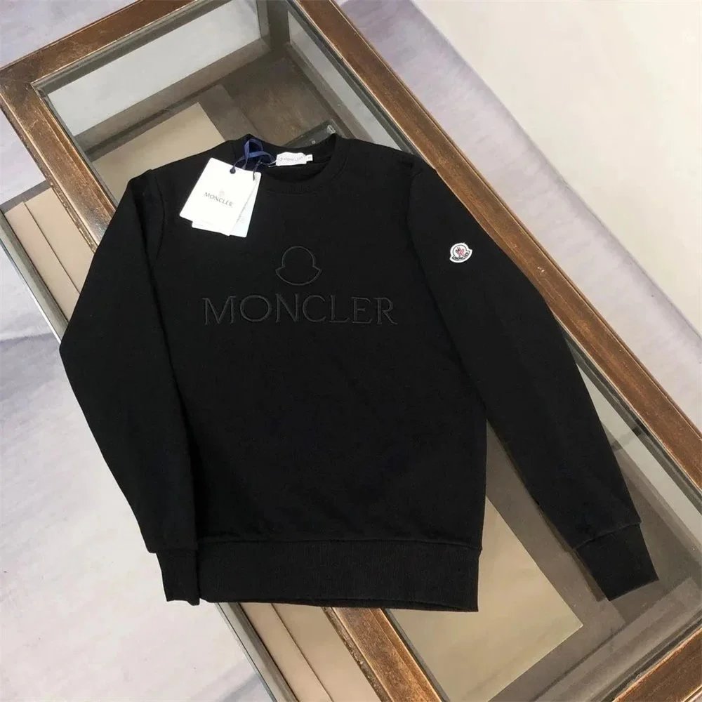 Black sweater with branding on a wooden surface