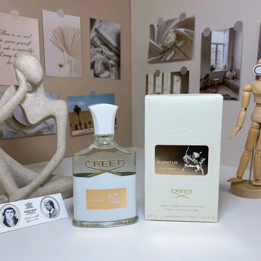 Creed perfume bottle and packaging on a surface with decorative items in the background
