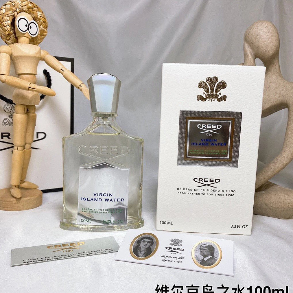 Creed Virgin Island Water perfume bottle and packaging on a white surface with decorative elements.
