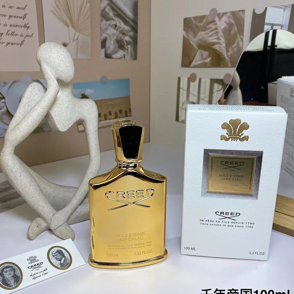 Creed perfume bottle and packaging on a white surface with decorative elements.