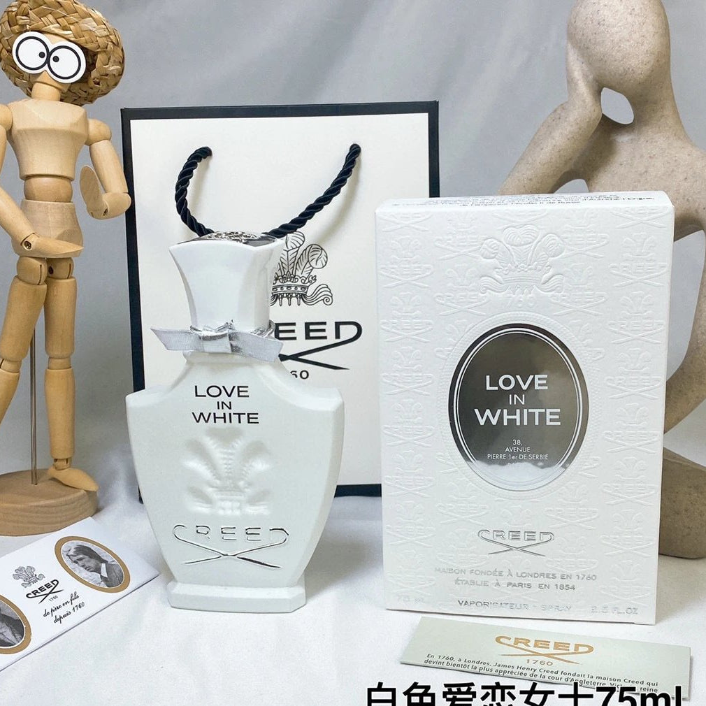 Creed Love in White perfume bottle and packaging on a white surface with decorative items.