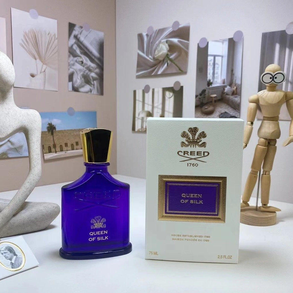 Creed Queen of Silk perfume bottle and packaging on a table with decorative items.