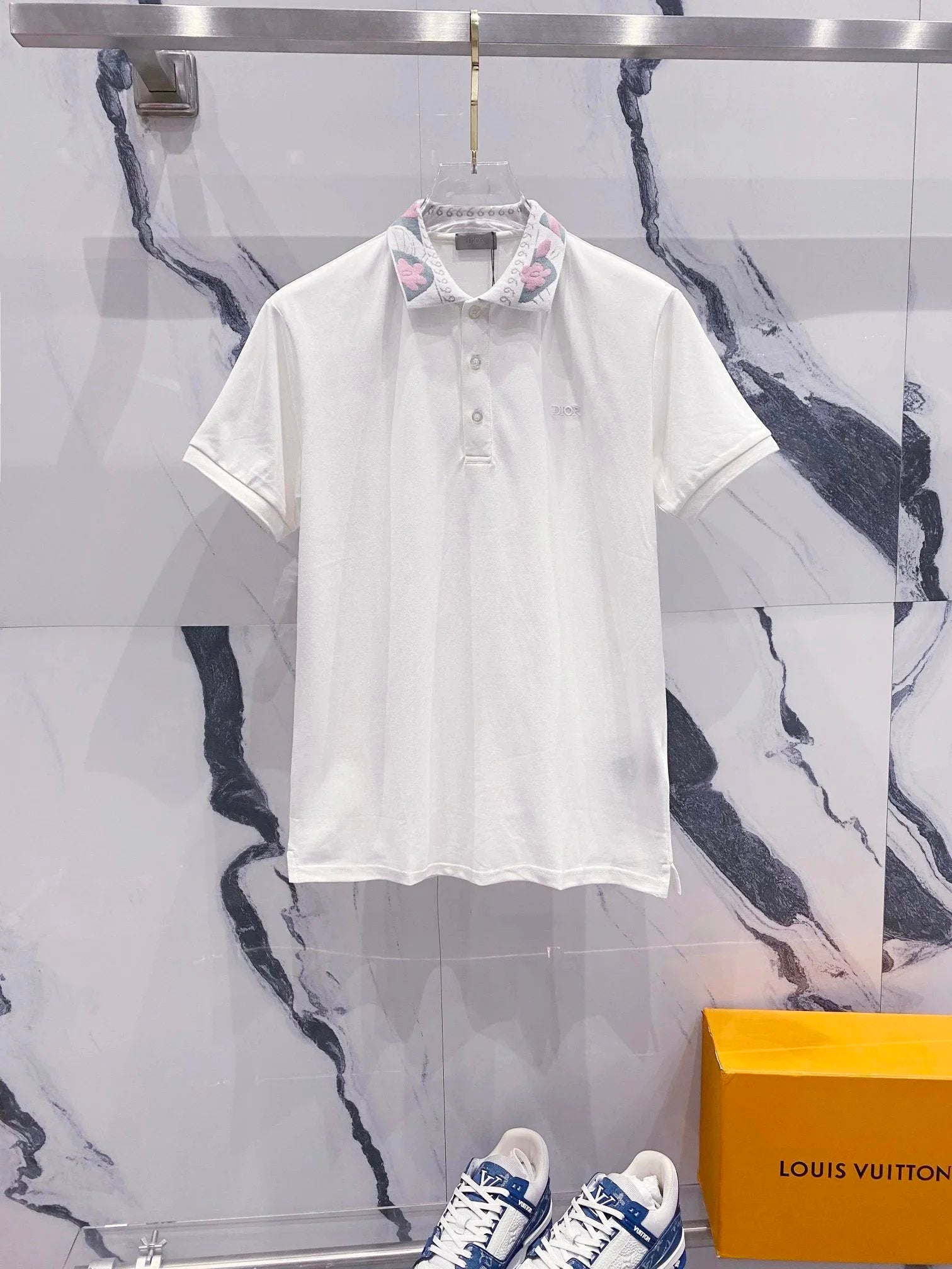 White polo shirt on a hanger with a marble wall background