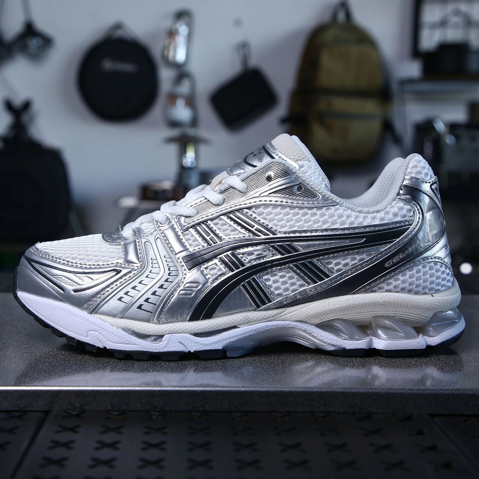 Silver and black athletic shoe on a reflective surface with a blurred background
