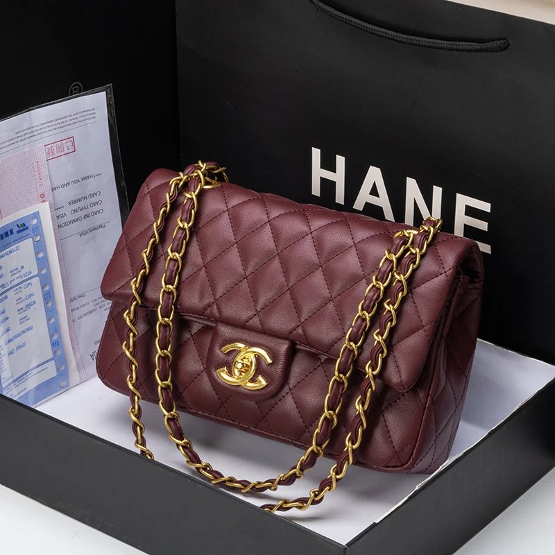 Maroon quilted handbag with gold chain and clasp on a black HANNEFORTH branded bag.