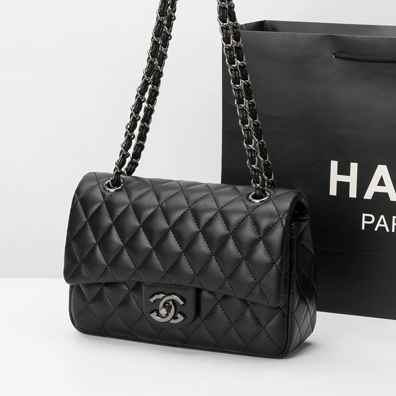 Black quilted handbag with chain strap in front of a black Chanel bag