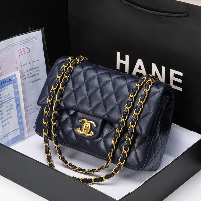Black quilted handbag with gold chain and Chanel logo on a black box.