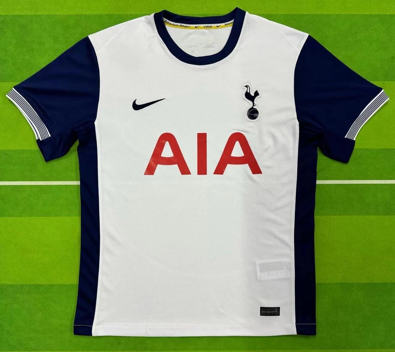 White and navy sports jersey with AIA logo on a green field background