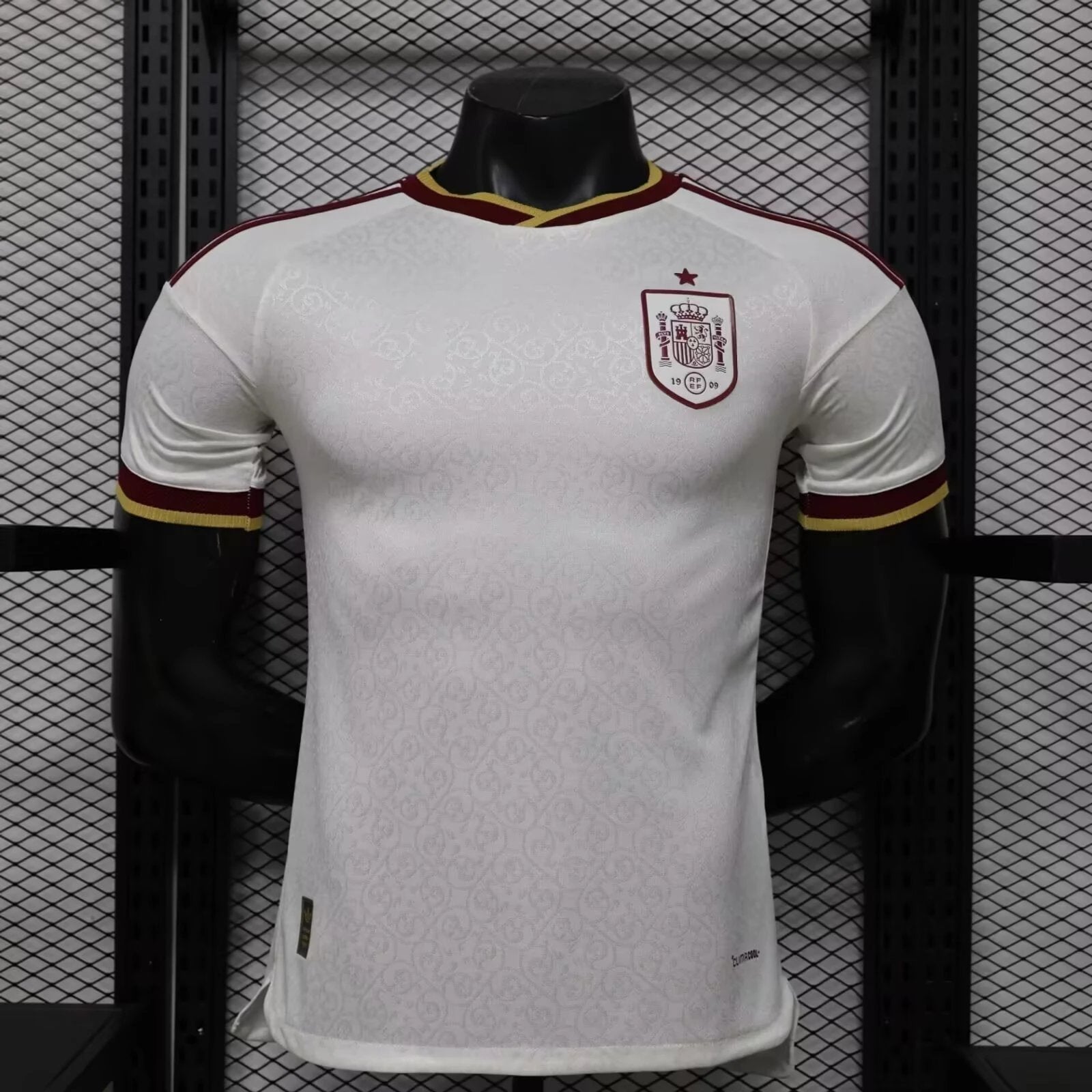 White sports jersey with red and yellow accents on a mannequin against a black metal grid background
