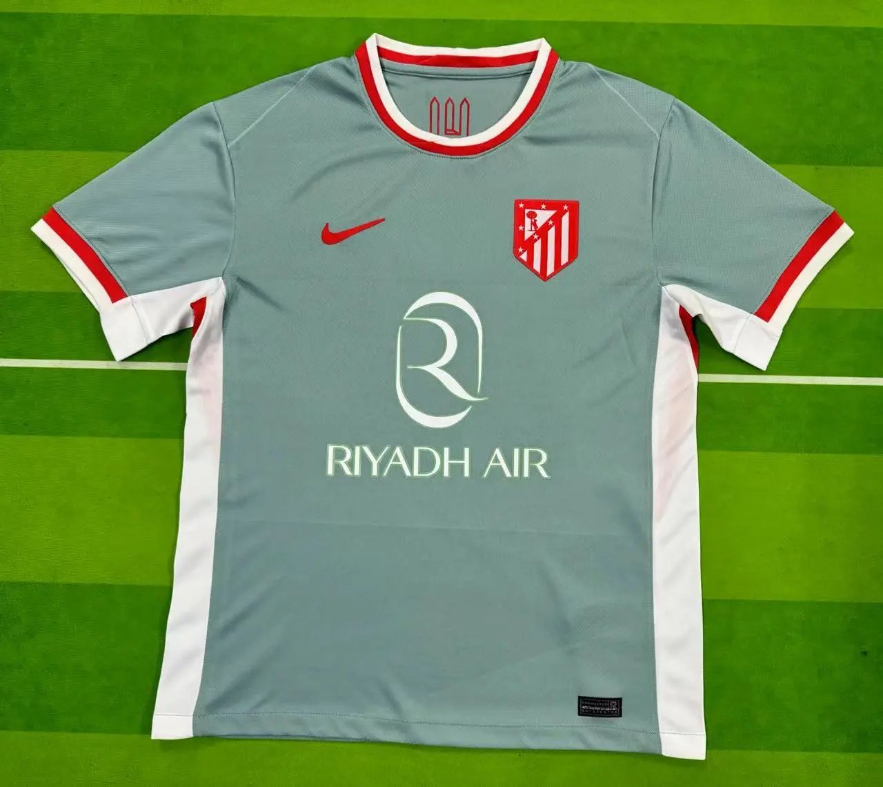 Gray sports jersey with red and white accents on a green field background