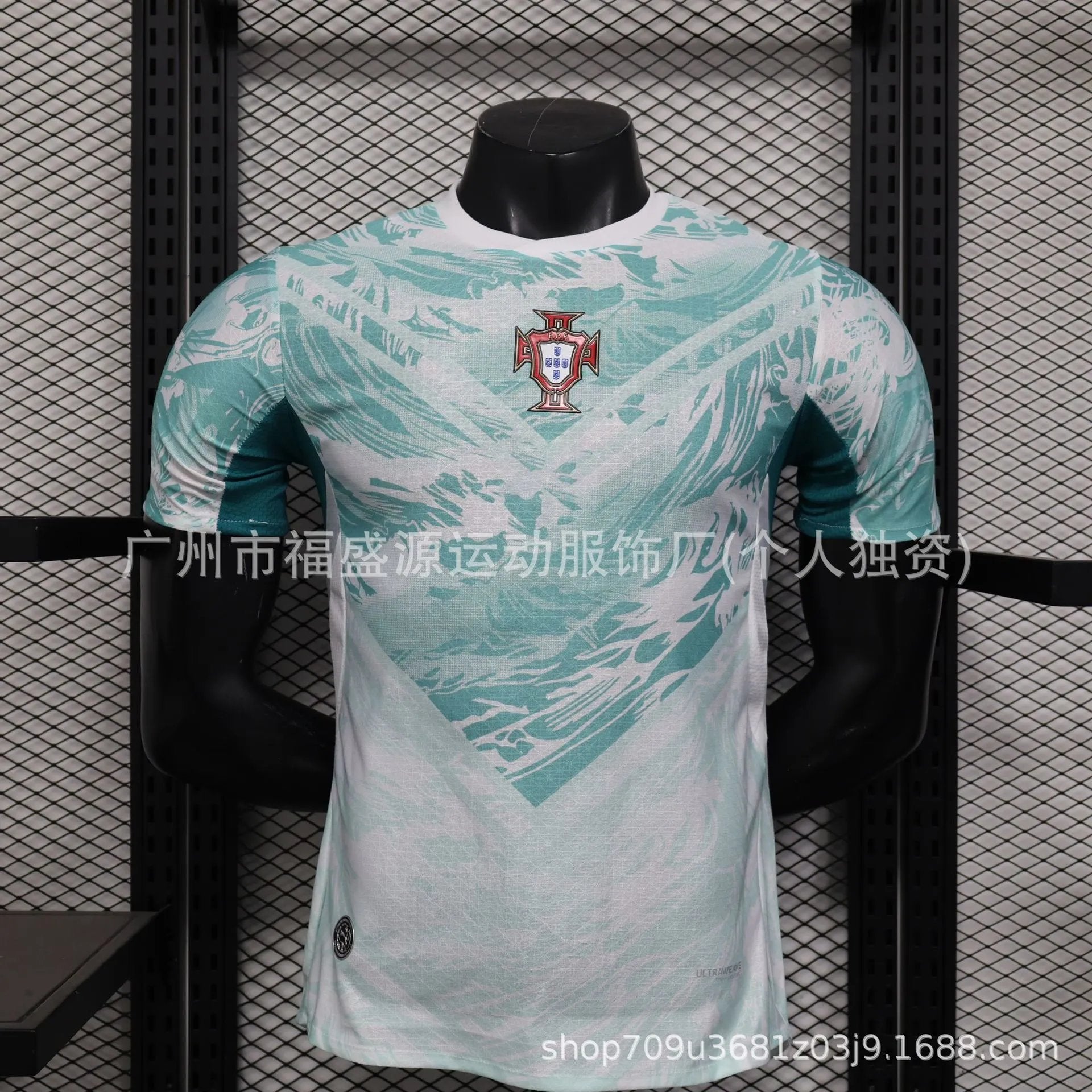 Light blue sports jersey with a logo on a mannequin against a black metal grid background.