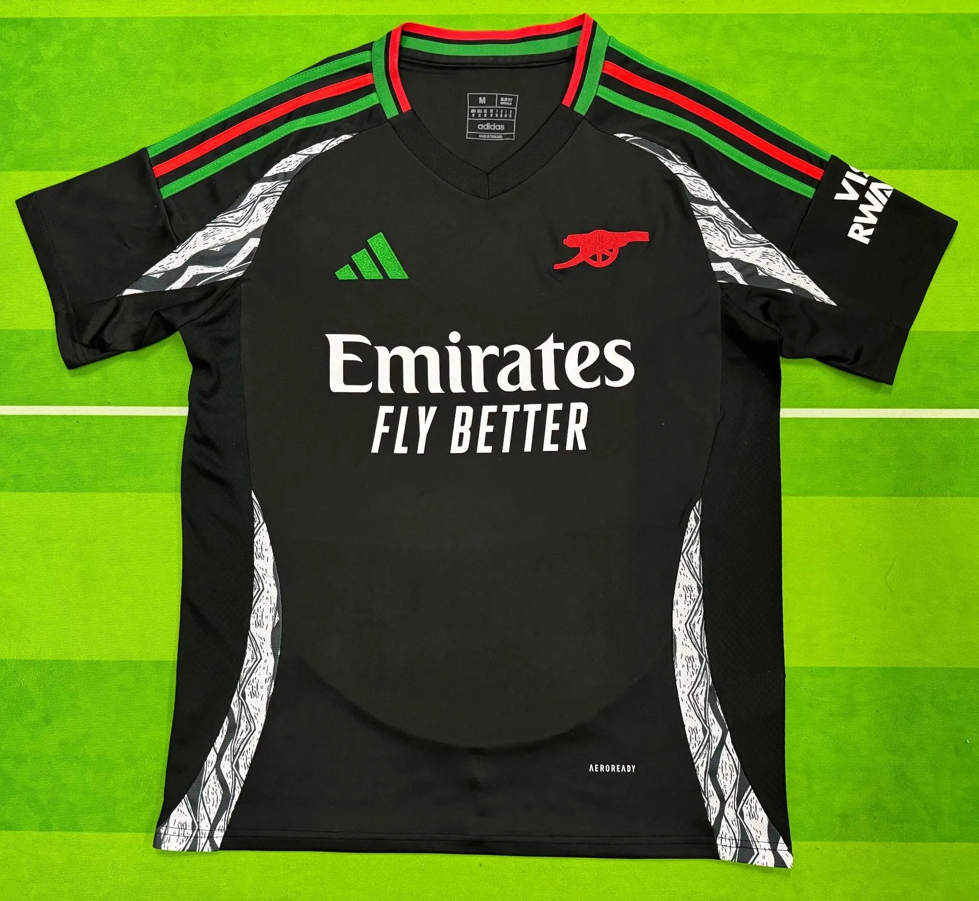 Black sports jersey with Emirates logo on a green background