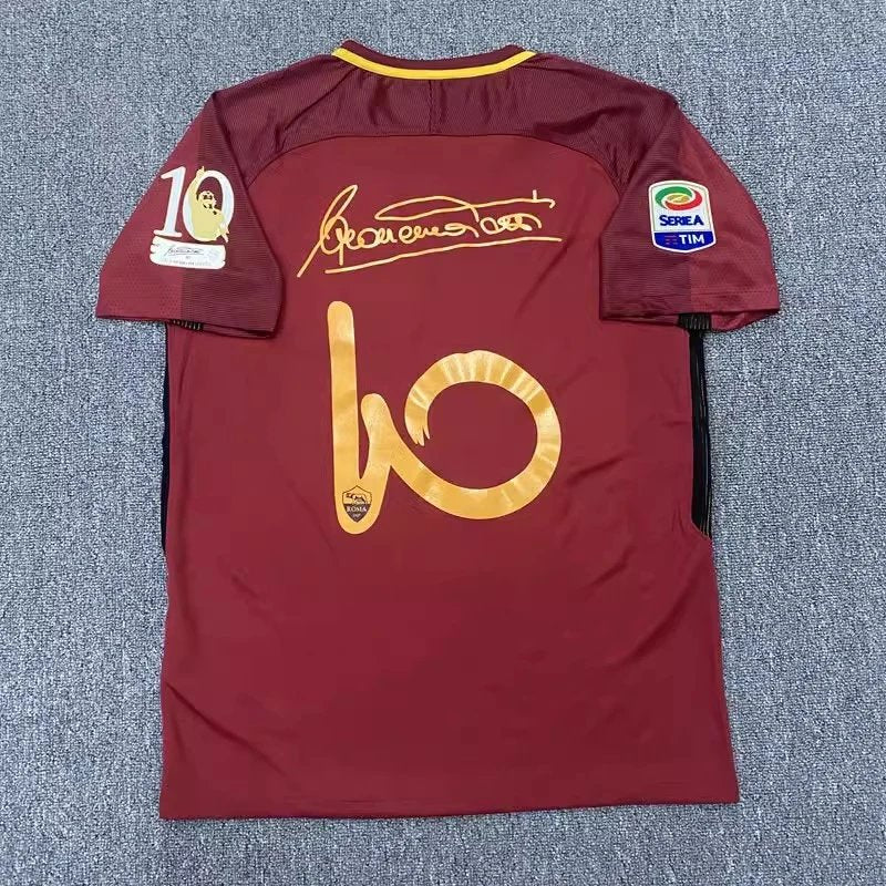 Maroon sports jersey with gold lettering on a textured gray background