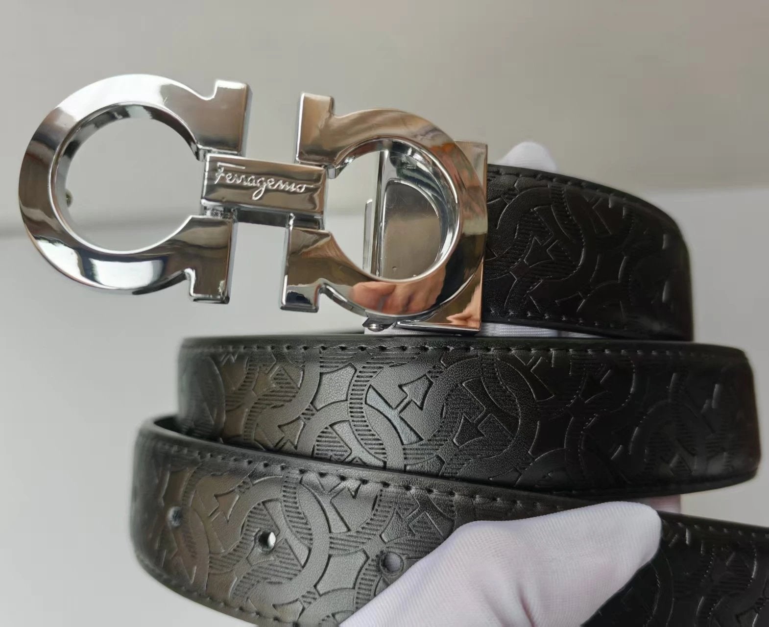 Black leather belt with silver Ferragamo buckle on a white background