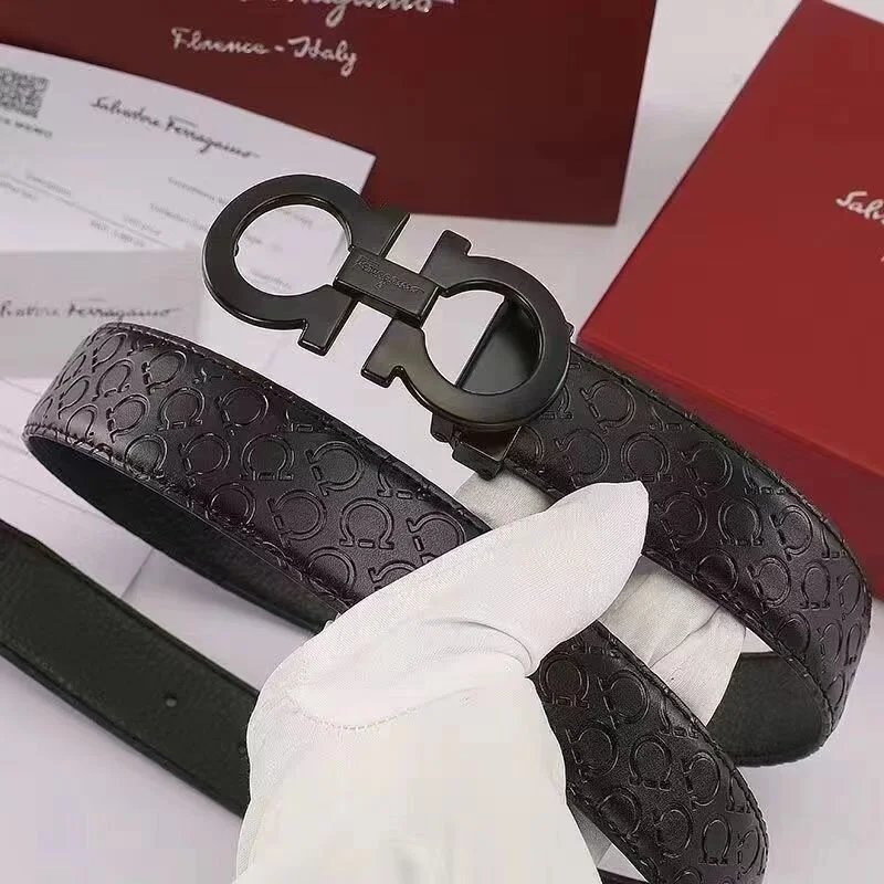 Black leather belt with Ferragamo logo held by a gloved hand, with a red box and white paper in the background.