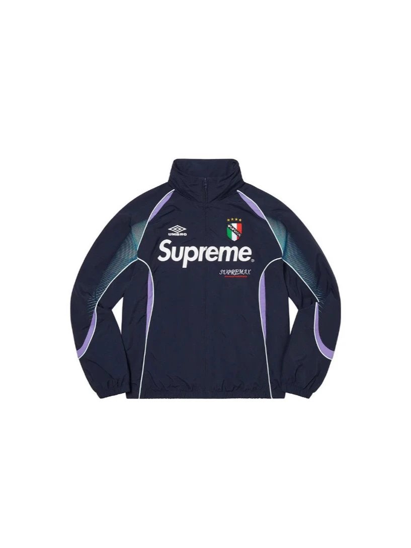 A navy blue track jacket featuring a high collar, with 'Supreme' printed in white across the chest, the Umbro logo on the right shoulder, and a small Italian flag crest. The jacket has purple and light blue geometric accents on the sides and sleeves, set against a plain white background.