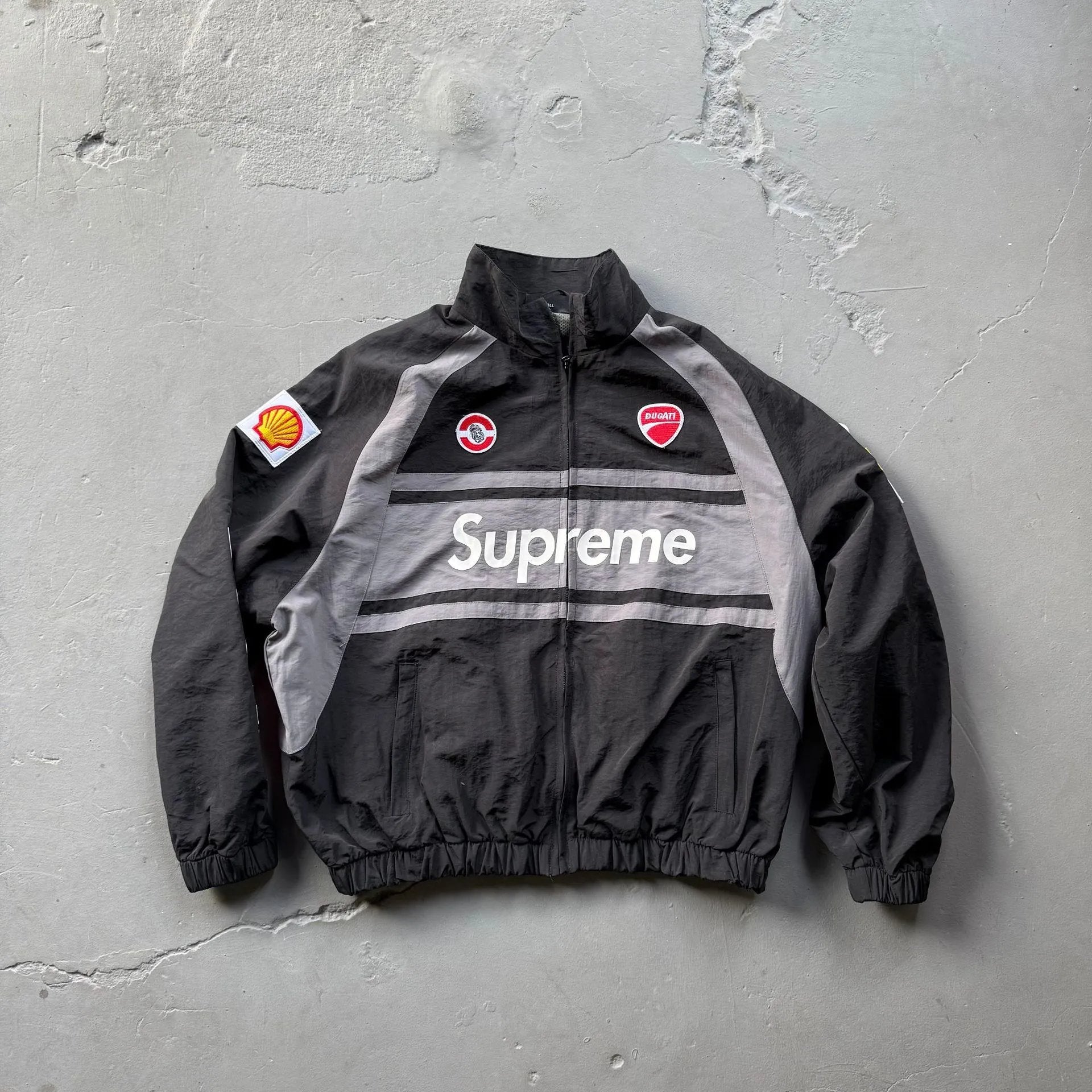 Black and gray jacket with 'Supreme' logo on a textured gray background