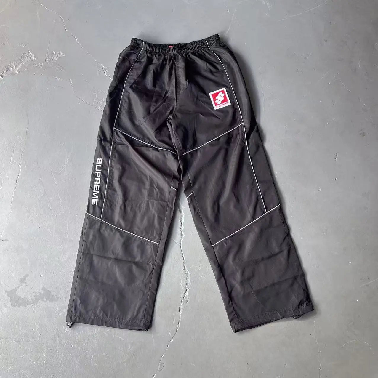 Dark gray pants with a logo on a gray background